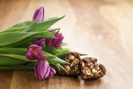 bouquet of purple tulips on wood table with homemade chocolate cookies for valentines day, shallow...