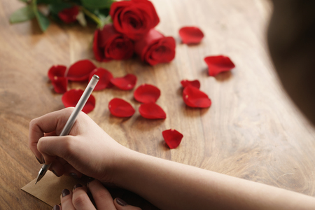 girl writes something on a paper card on old wood background, shot from aboveの写真素材
