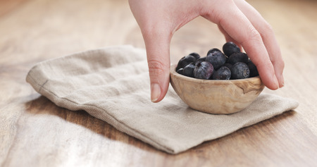 young female hand putting bowl of blueberries on table, 4k photo