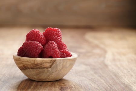 ripe organic raspberries in wood bowl on old wooden table, with copy spaceの写真素材