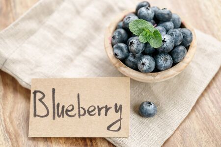 fresh blueberries in bowl with paper card on wood table with sack cloth, organic natural foodの写真素材