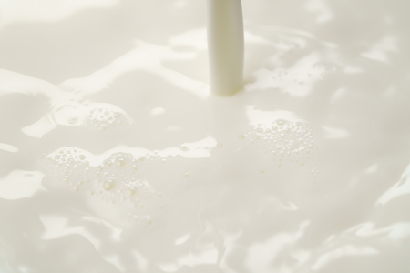 pouring milk into bowl from above, closeup photoの写真素材