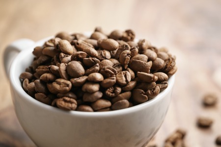 cappuccino cup with roasted coffee beans on wood table, closeupの写真素材