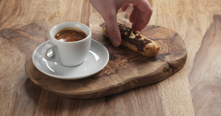 man hand bring espresso and eclair with hazelnuts, 4k photoの写真素材