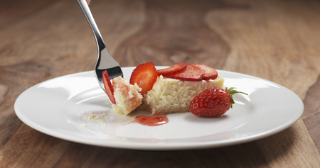 eating strawberry cheesecake with fork on wood table, 4k photoの写真素材
