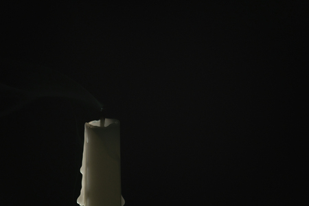 tall candle with smoke trail over black background, simple photoの写真素材