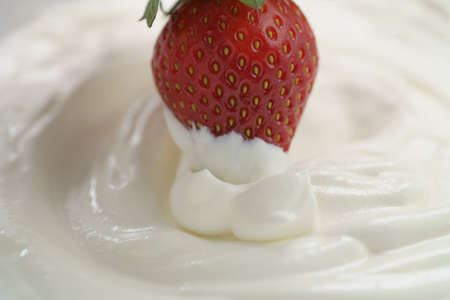 dipping fresh strawberry into cream, delicious foodの写真素材