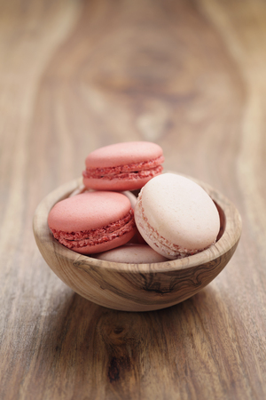pastel colored macarons with strawberry and rose flavour in wood bowl on tableの写真素材