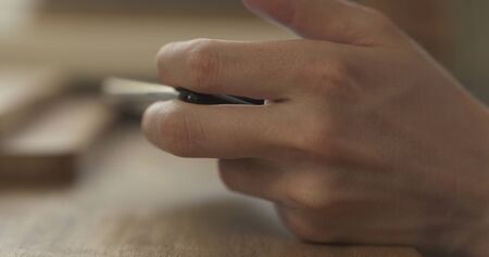 young man hands using smartphone sitting at the table closeup, 4k photoの写真素材
