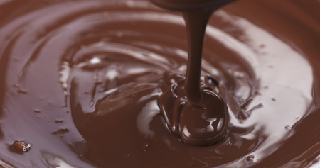 Slow motion of premium dark melted chocolate being poured from spoon in right part of frame, 4k photoの写真素材