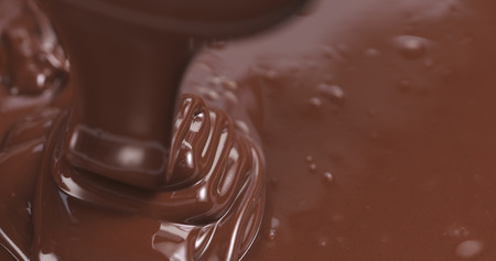 Slow motion of premium dark melted chocolate being poured from spoon in left part of frame, 4k photoの写真素材