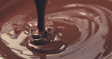 premium dark melted chocolate being poured from spoon closeup toned, 4k photoの写真素材