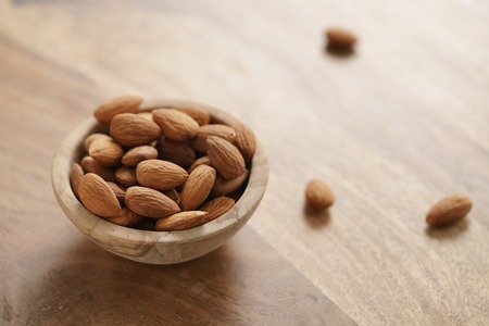 organic almonds in wood bowl on wooden table, shallow focusの写真素材