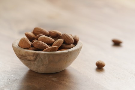 organic almonds in wood bowl on wooden table, shallow focusの写真素材