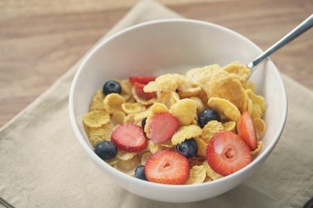 spoon with healthy breakfast with corn flakes and berries, slightly toned photoの写真素材