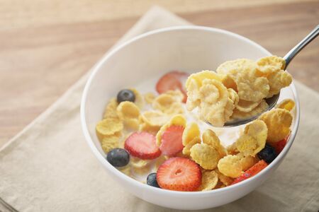 spoon with healthy breakfast with corn flakes and berries, slightly toned photoの写真素材