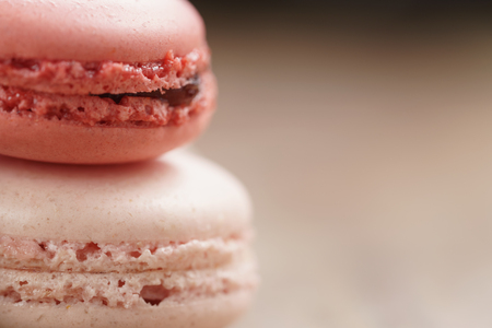 closeup shot of pink pastel colored macarons on wood table, vintage toned photoの写真素材