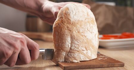 young man hands cutting ciabatta bread for making sandwich, 4k photo