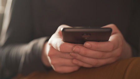 teen girl using smartphone backlit by window light, uhd photoの写真素材