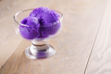 purple sorbet ice cream on wood table in glass bowl, shallow focusの写真素材