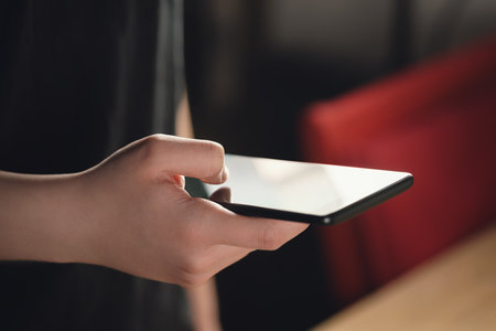 female teen hand holding smartphone closeup shot, shallow focusの写真素材