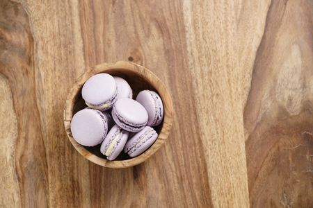 violet macarons in wood bowl on wooden table from above, with copy spaceの写真素材