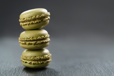 pistachio macarons stacked on slate board with copy space