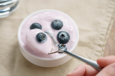 pov teen girl hand eating organic blueberry yogurt, shallow focusの写真素材
