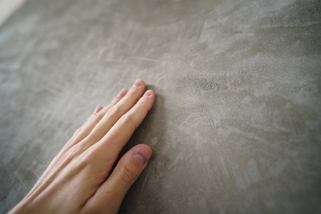 young man hand touching concrete wall, closeup photo