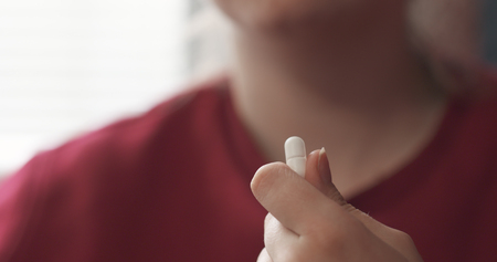 handheld teen girl taking pillの写真素材