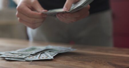front shot of man counting dollars on wood table
