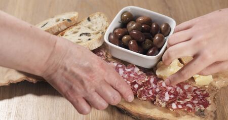 three hands taking italian antipasti appetizers from table, wide photo