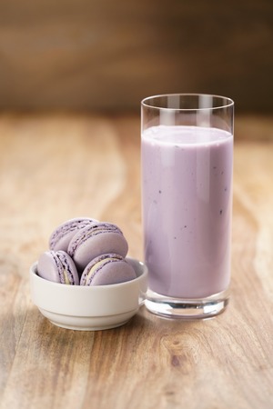 violet macarons in white bowl with blueberry yogurt on wooden tableの写真素材