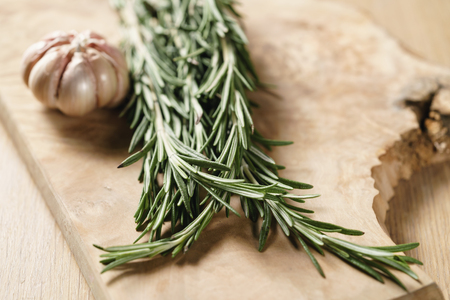 fresh rosemary bunch and garlic on wood table, shallow focusの写真素材