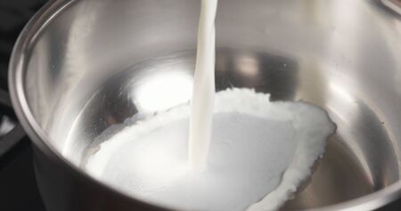 shot of pouring milk into saucepanの写真素材