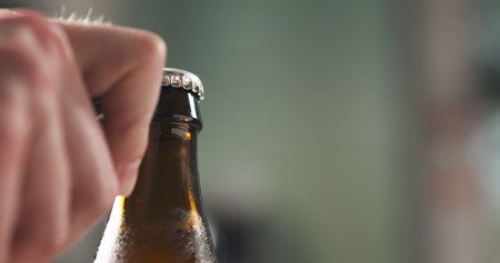 man hand opening brown beer bottle closeupの写真素材
