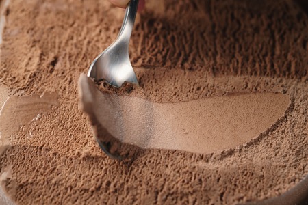 closeup scooping chocolate ice cream with spoonの写真素材