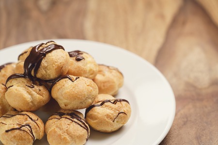profiteroles with fine dark chocolate on plateの写真素材