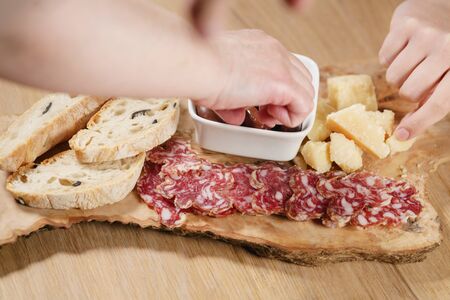 hands taking italian antipasti appetizers on tableの写真素材