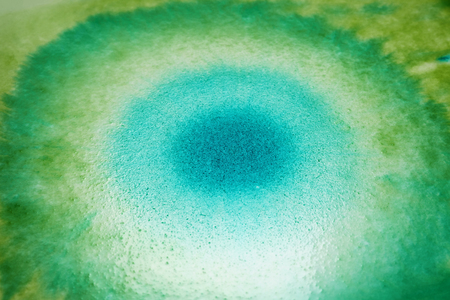 closeup green and blue ink spreading on wet paper angle view