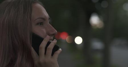female teen talking on the phone on the street at nightの写真素材