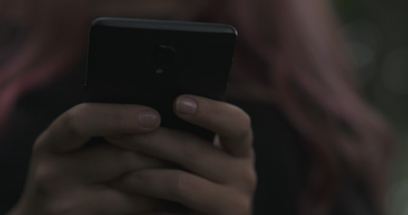 female teen using smartphone on the street at night, wide photo