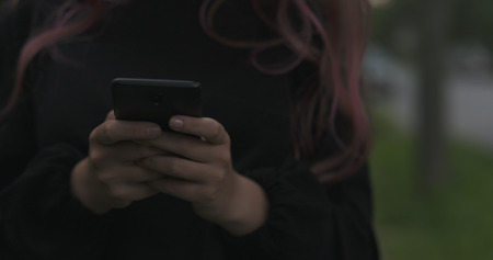 female teen using smartphone on the street at night, wide photoの写真素材