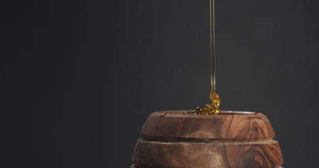 honey drips from dipper in pot, wide photoの写真素材