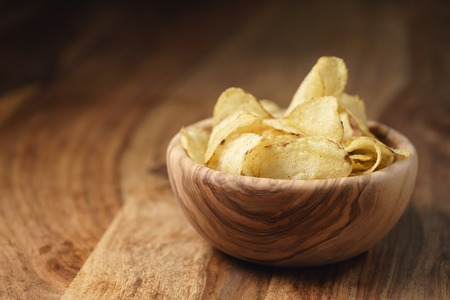 natural potato chips with black pepper in wood bowl on table with copy spaceの写真素材