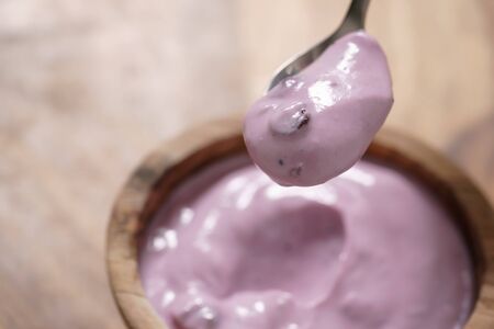 eating blueberry yogurt from wood bowl, closeup shotの写真素材
