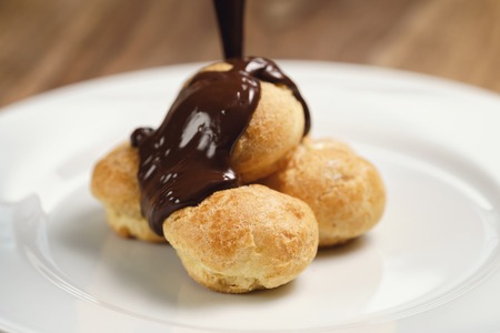 pour chocolate on profiteroles on plate closeupの写真素材