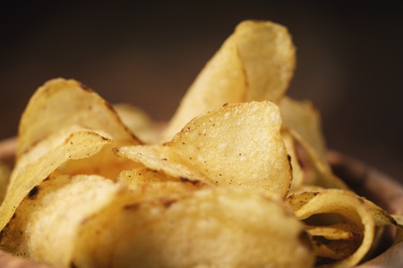 closeup potato chips with herbs in wood bowl on rustic table, simple photo