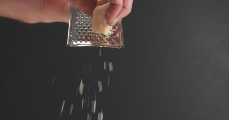 closeup of grating aged parmesan over dark backgroundの写真素材