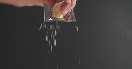 closeup of grating aged parmesan over dark backgroundの写真素材
